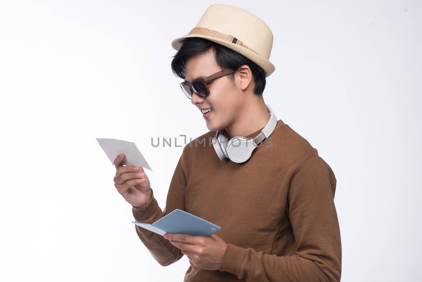 Happy young tourist asian man holding passport over grey background