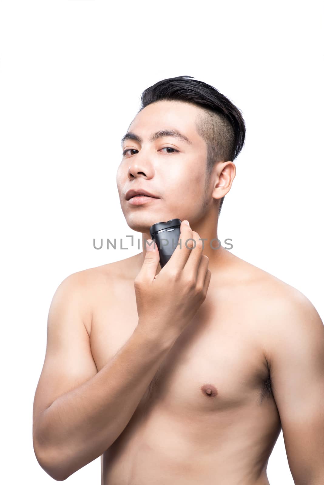 Young asian man shaving over white background and looking at camera
