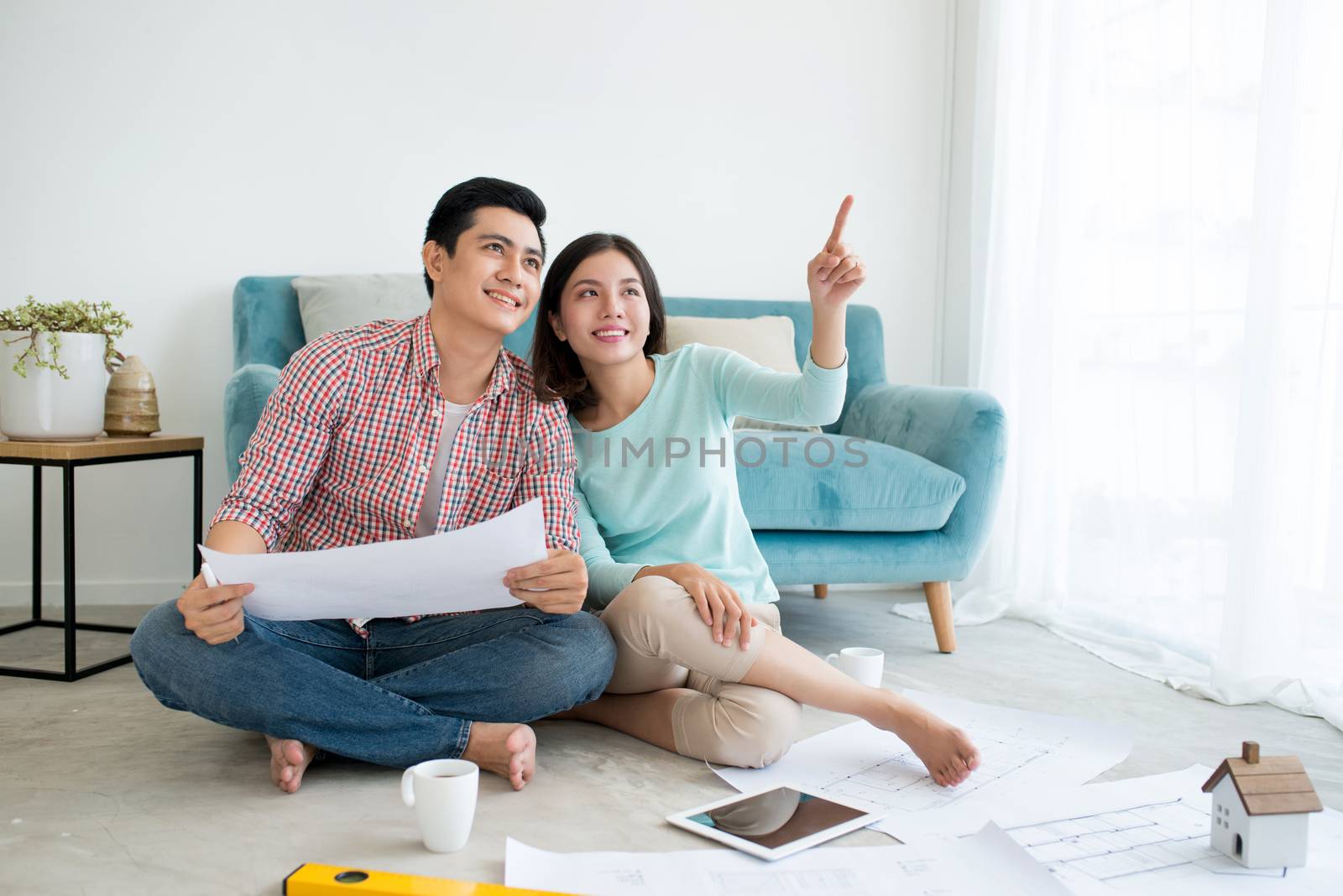 Attractive young asian adult couple planning new home design. by makidotvn