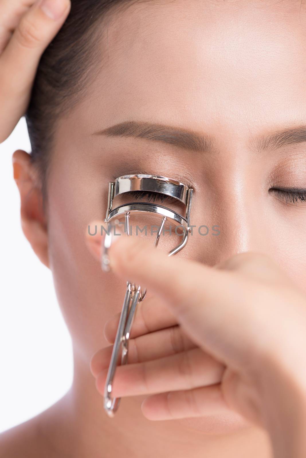 Make-up artist curling eyelash for asian model.