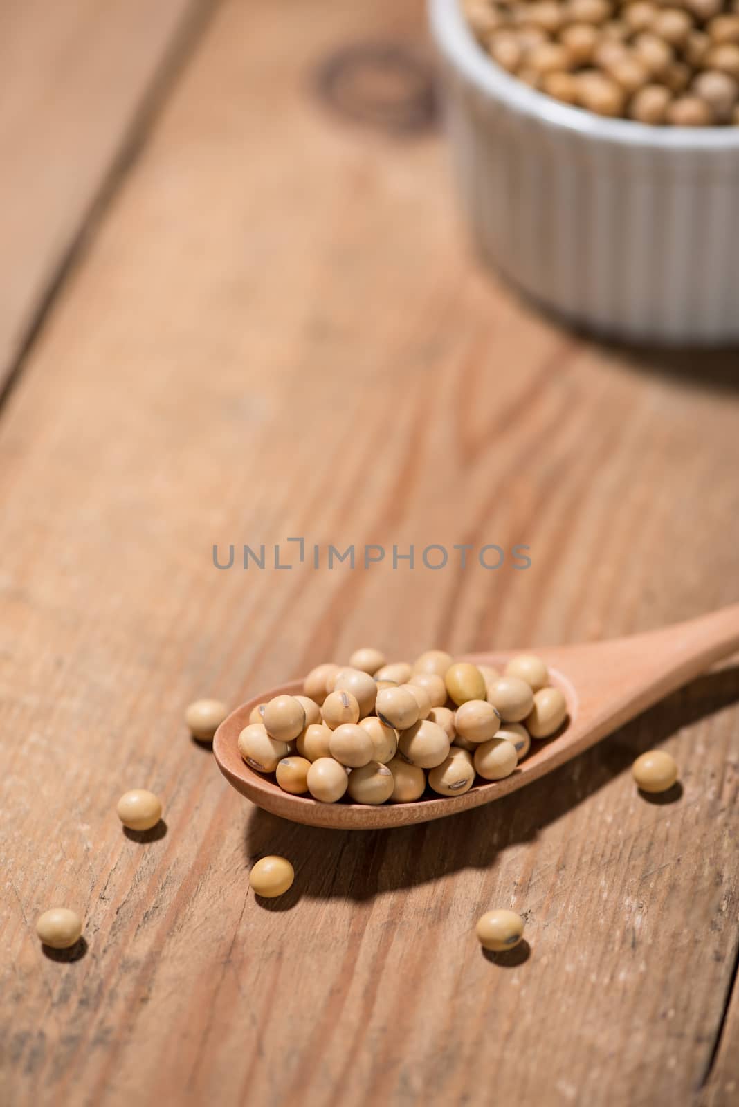 Soya beans in spoon on wooden table. by makidotvn