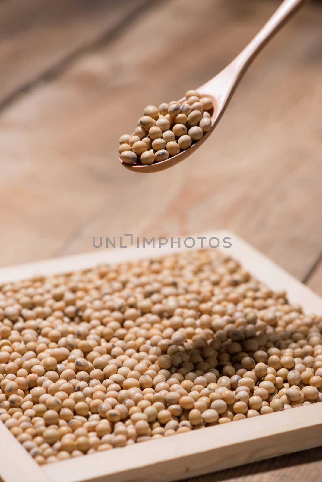 Soya beans in spoon on wooden table.