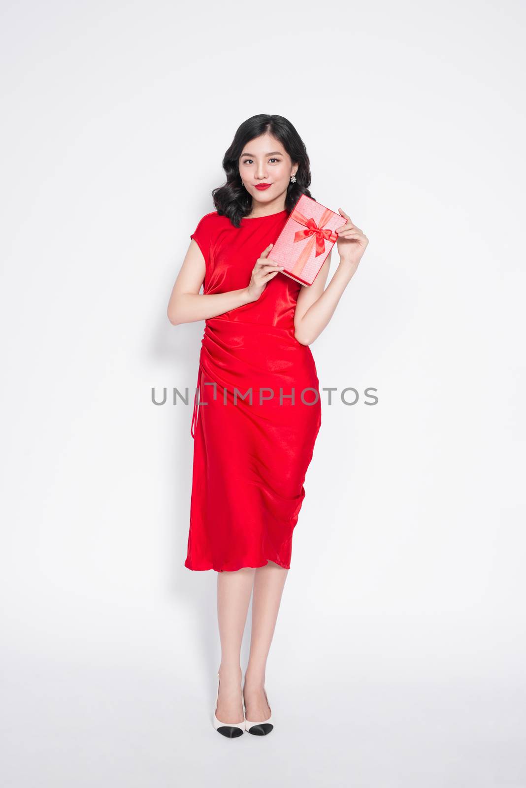 Pretty young asian woman dressed in red dress with a present