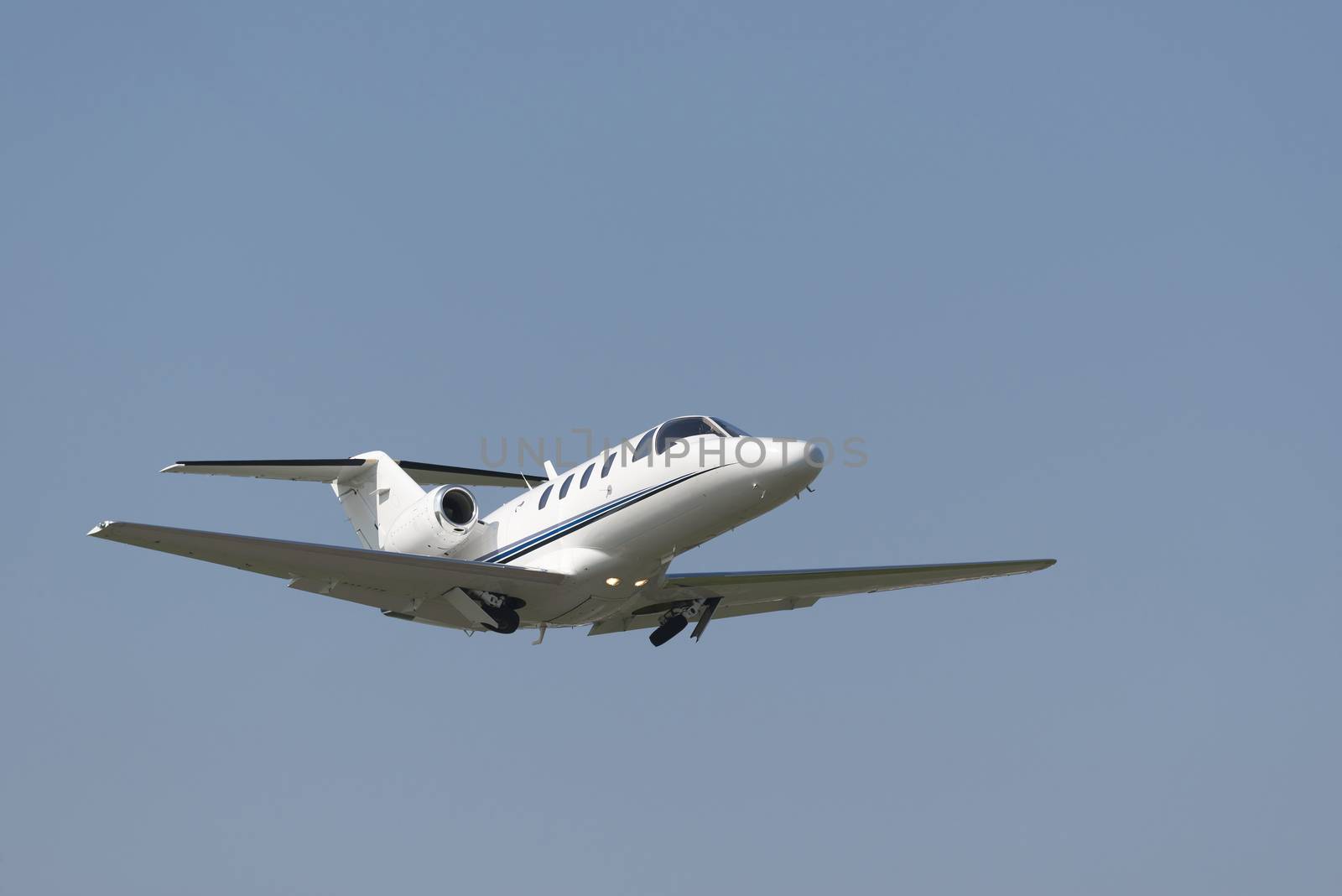 Business Jet directly after takeoff accelerating with withdrawing landing gear
