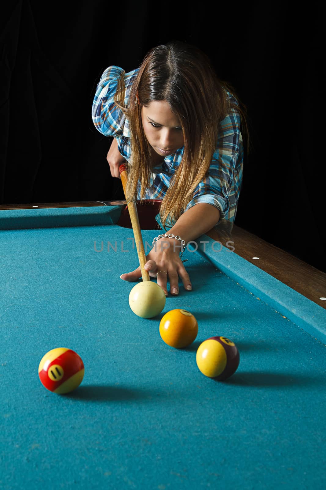 twenty something beautiful girl wearing a low cut plaid shirt about to shoot pool