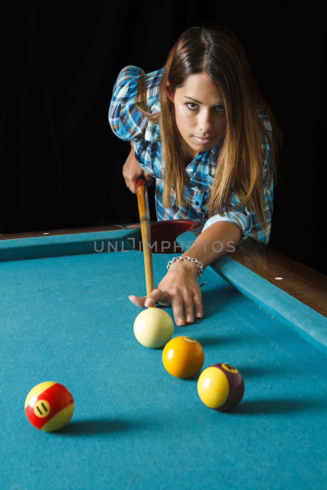 twenty something beautiful girl wearing a low cut plaid shirt about to shoot pool
