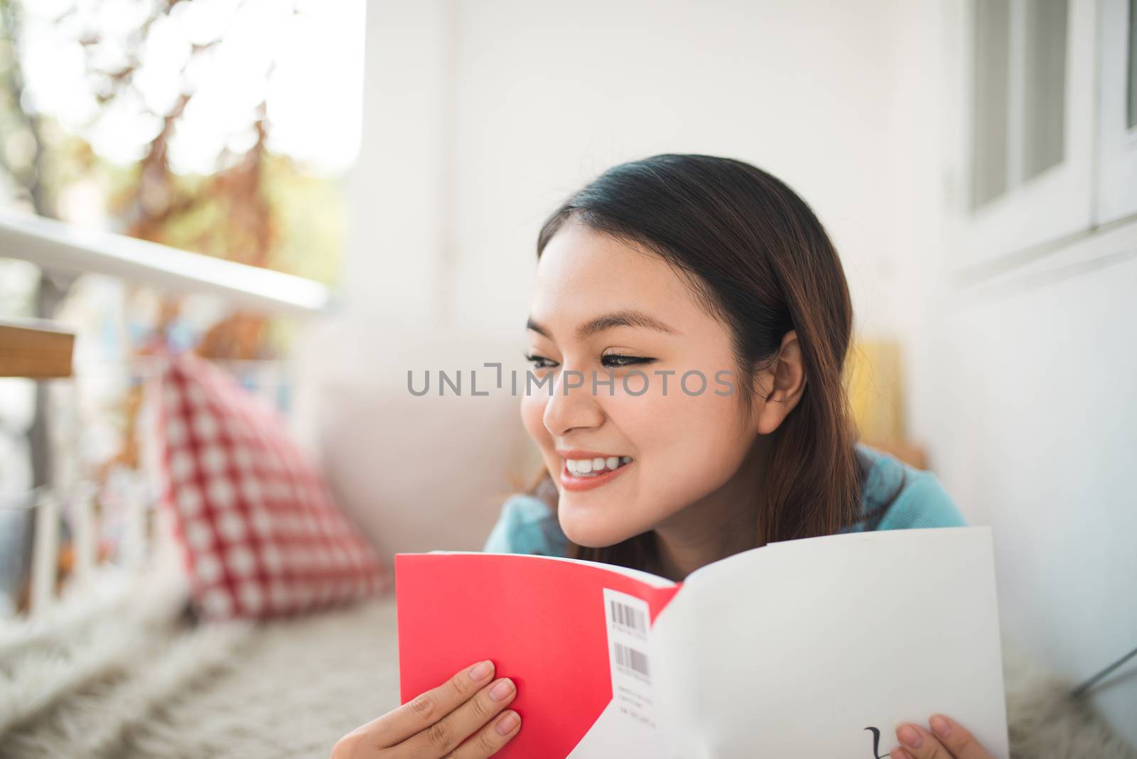 Portrait of young asian woman reading book at home