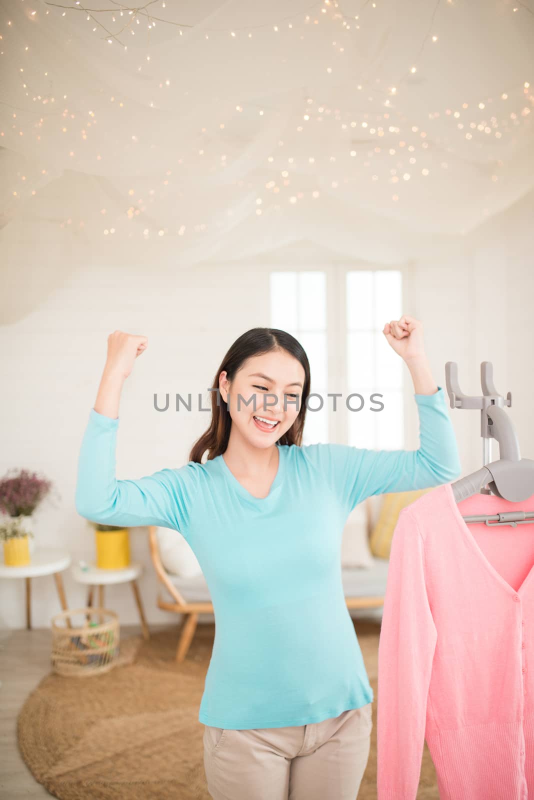 Happy young asian woman finish steaming clothes in room