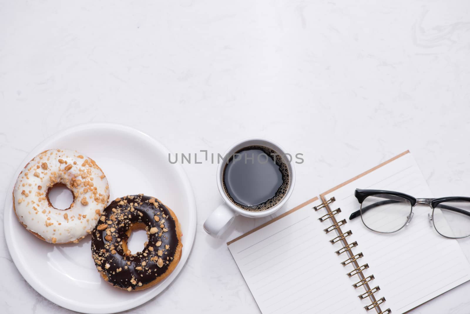 Working desk with dessert and coffee. Cake donuts with a cup of espresso on marble table top. 