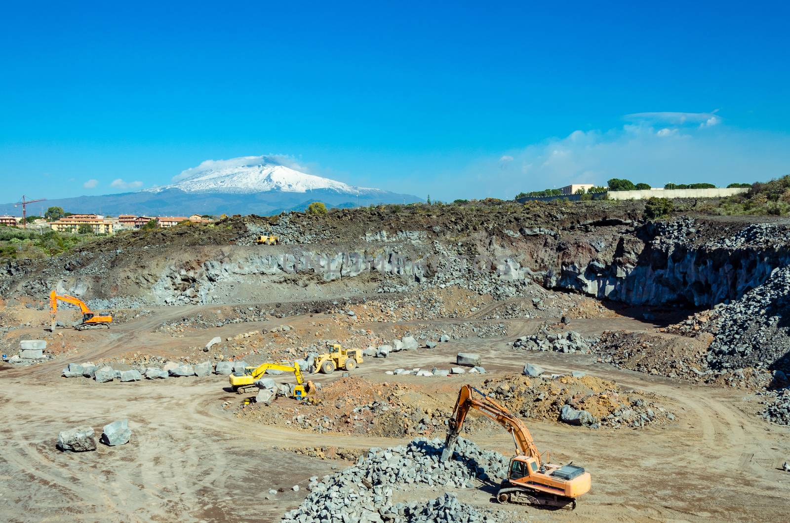 the excavator in a sicilian mine in a day's work. On background the volcano Etna