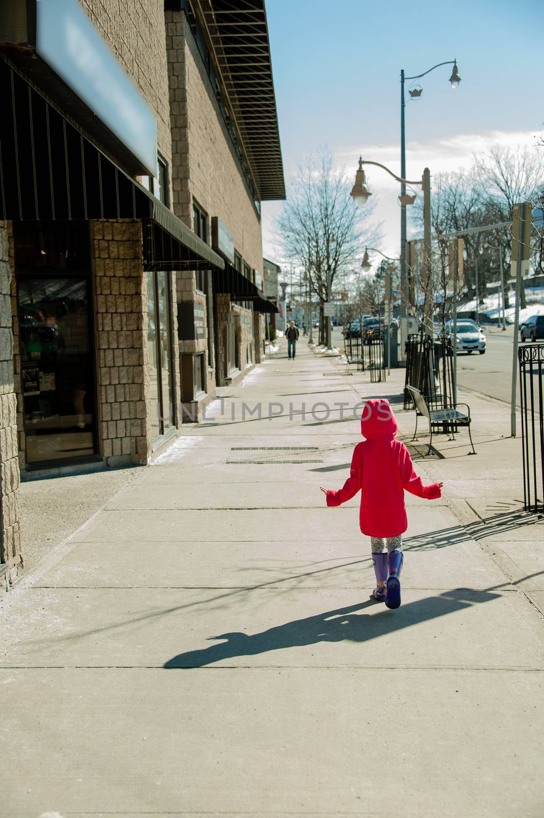  A girl in a red jacket walks the city on the first spring day