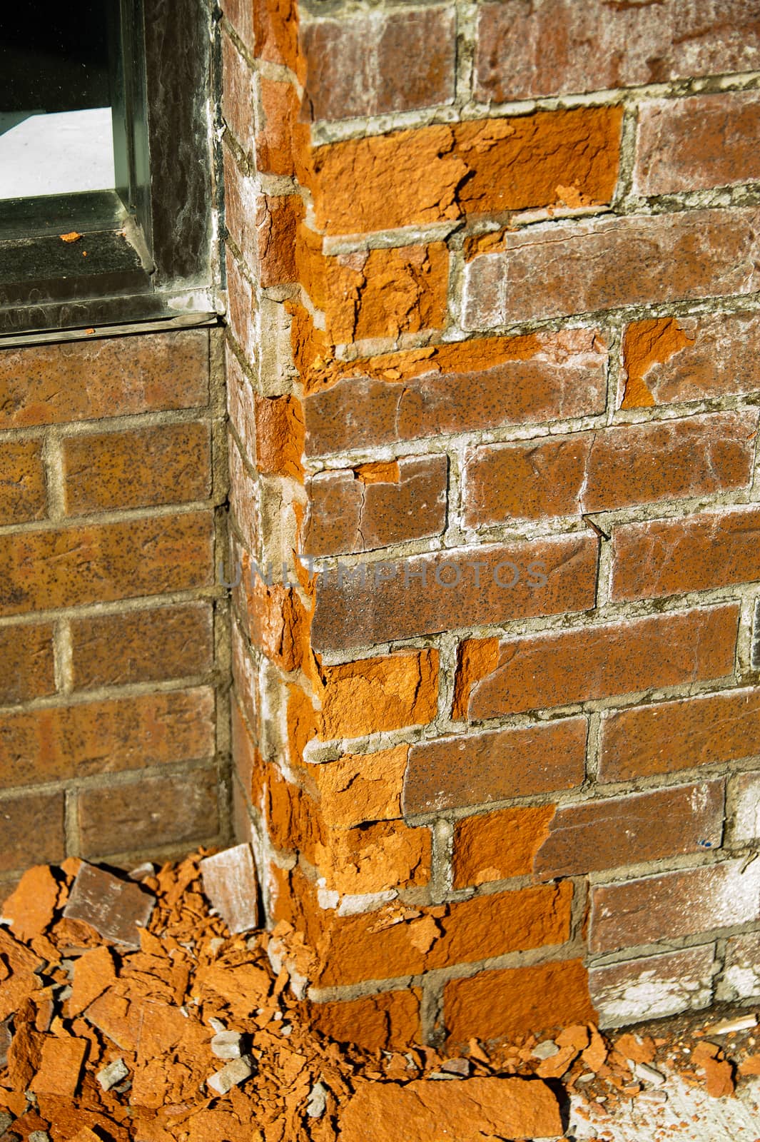 Fragment of the wall of red brick, where the bricks began to crumble from moisture and frosts