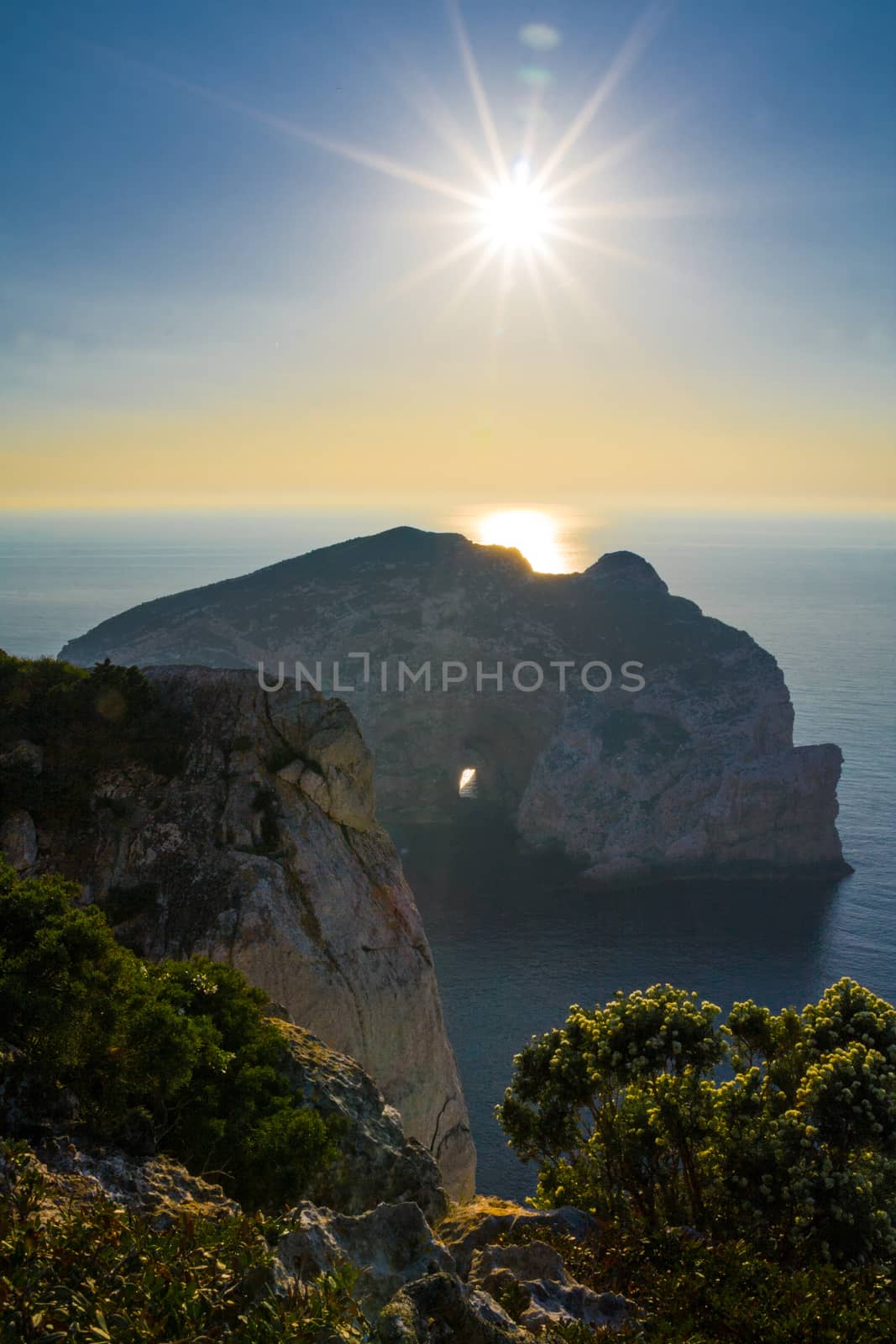 Sunrise behind the cliff with the hole. Sardinia by rainfallsup