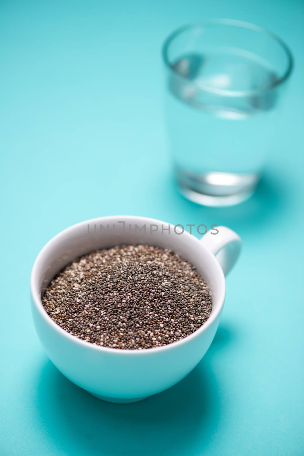 Glass of water and healthy chia seeds in a cup. Text space.