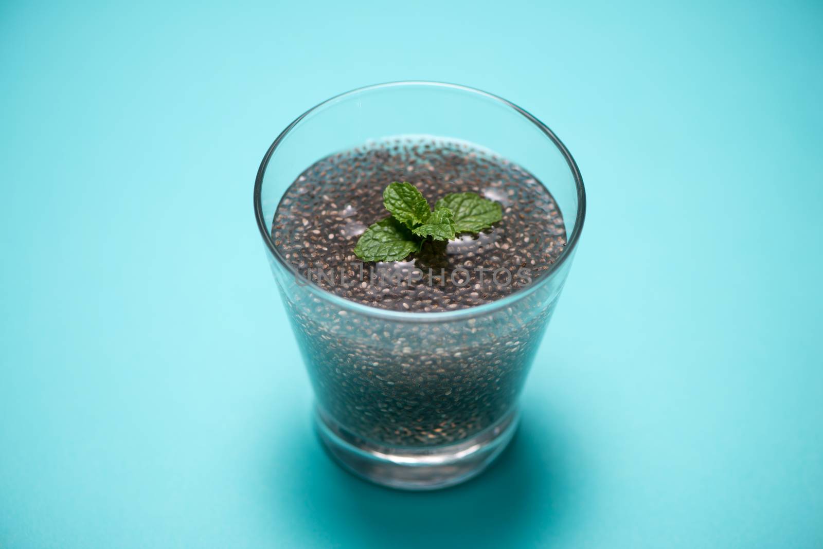 Glass of water with cup of healthy chia seeds and spoon. Text sp by makidotvn