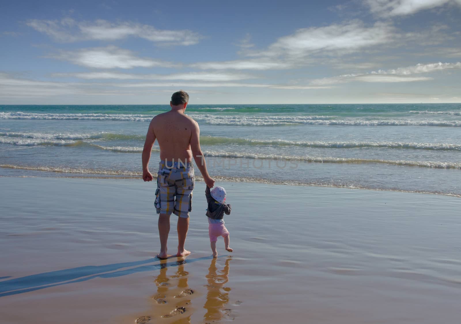 Father and baby touch the ocean