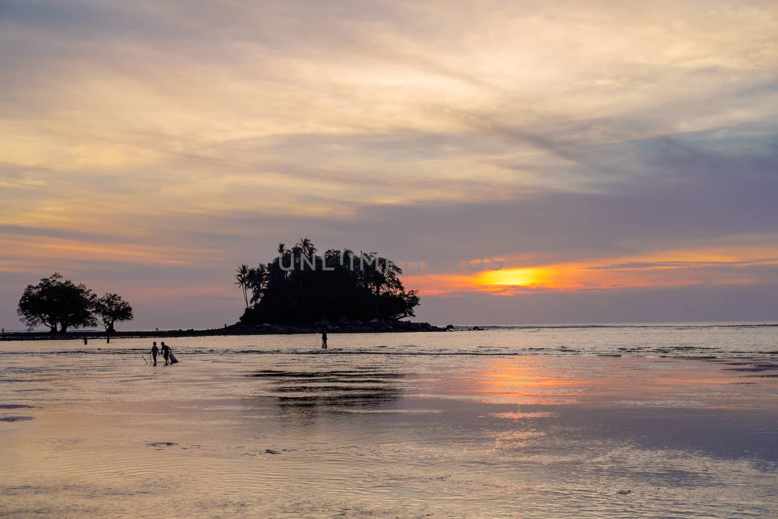 Fisherman with his family is checking nets in the beautiful sunset near tropical island. Phuket. Thailand