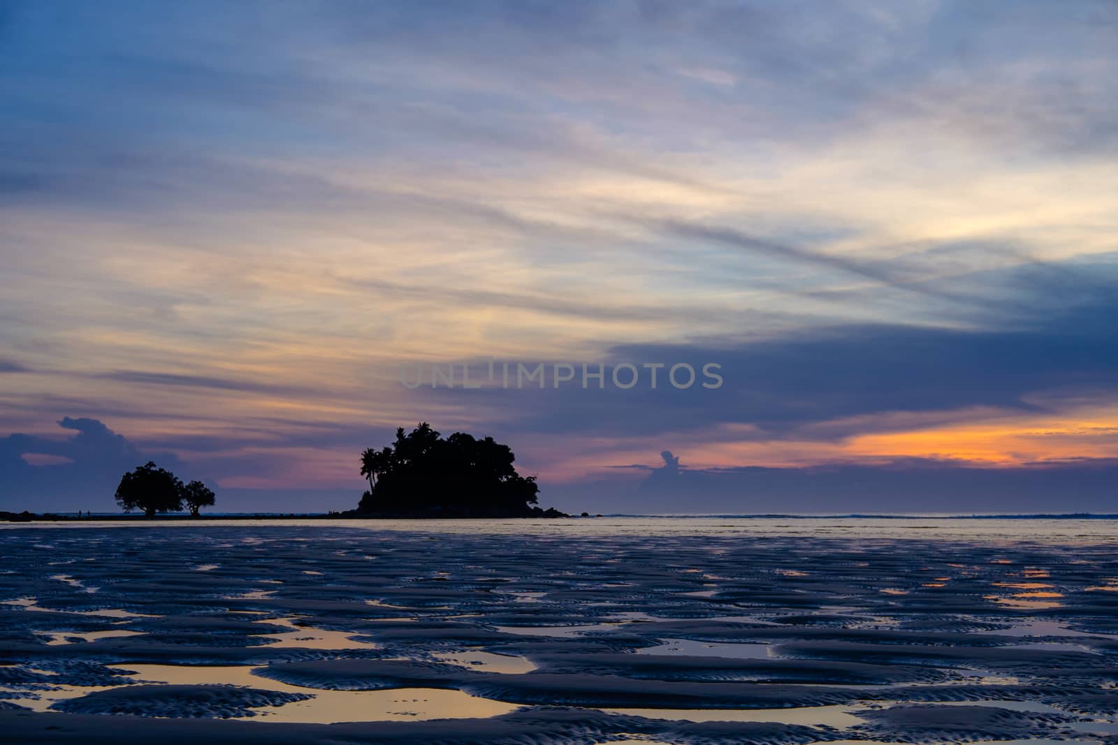 Beautiful colorful sunset near the small exotic island with palms