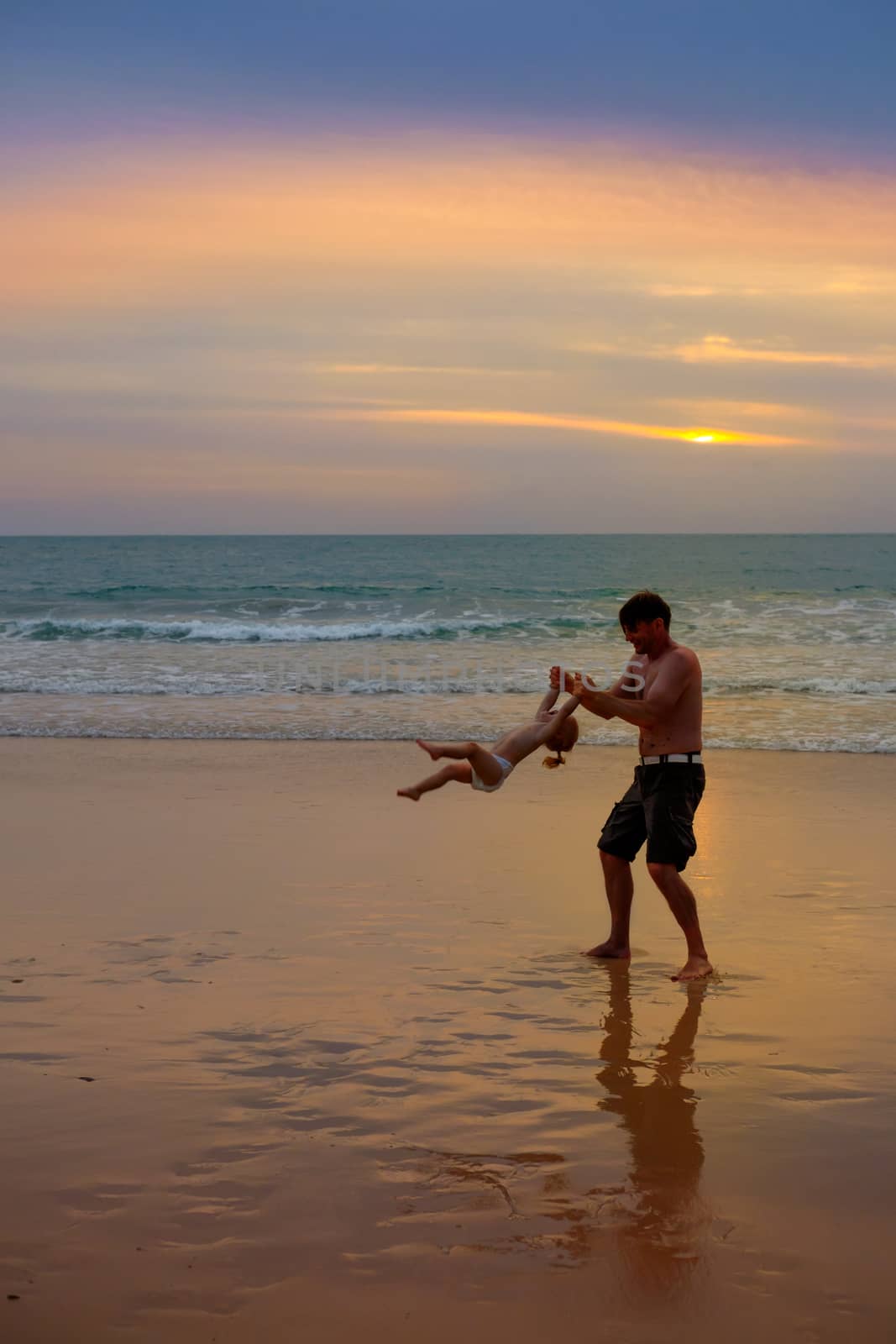 Father plays with his daugter at the beach near the sea at the s by rainfallsup