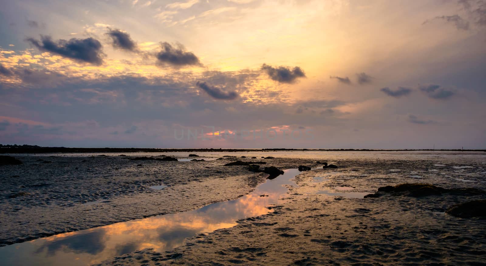 Colourful sunrise and stream in  low tide ocean water by rainfallsup