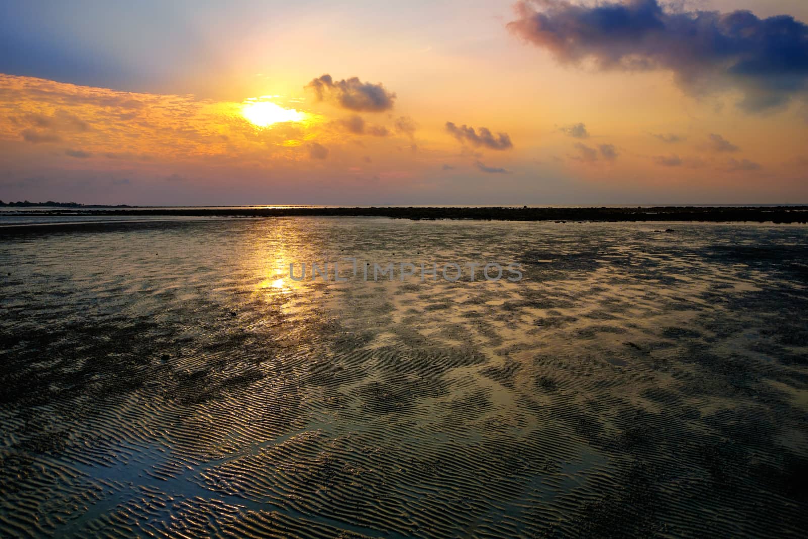 Colourful sunrise and the sand during low tide ocean water by rainfallsup