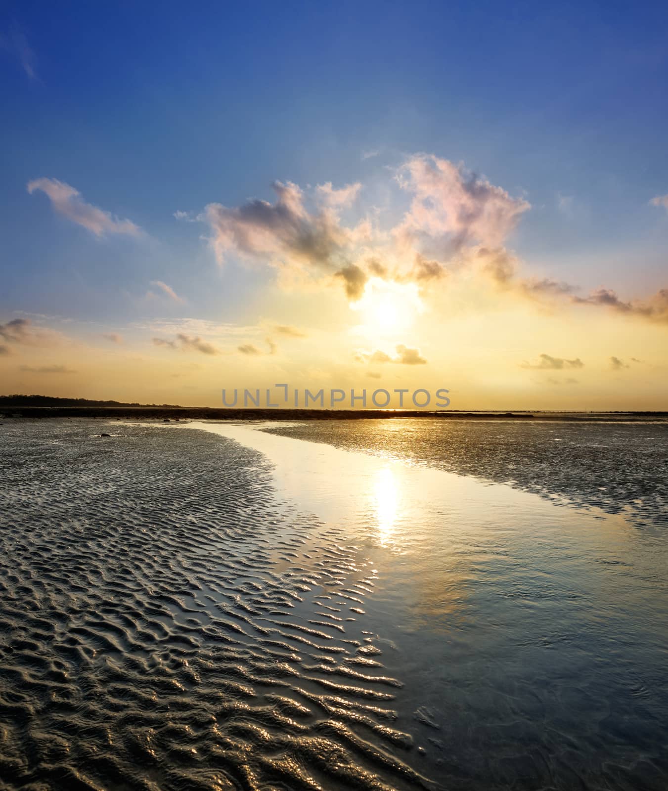 Colourful sunrise and the sand during low tide ocean water