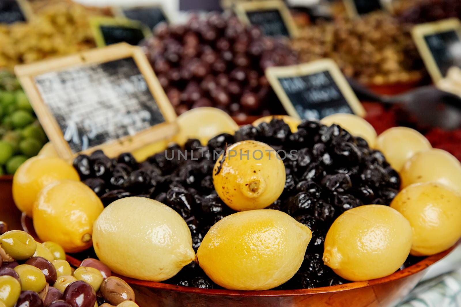 Mix of Olives with limon in wooden bowl at the food market in Pa by pixinoo