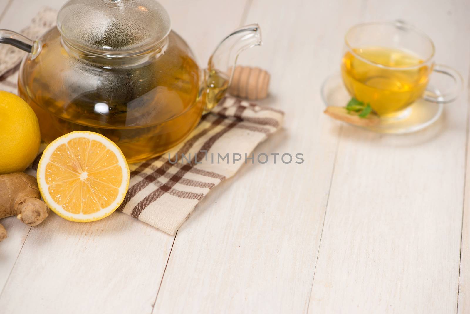 Cup of ginger tea with lemon and honey on white wooden background.