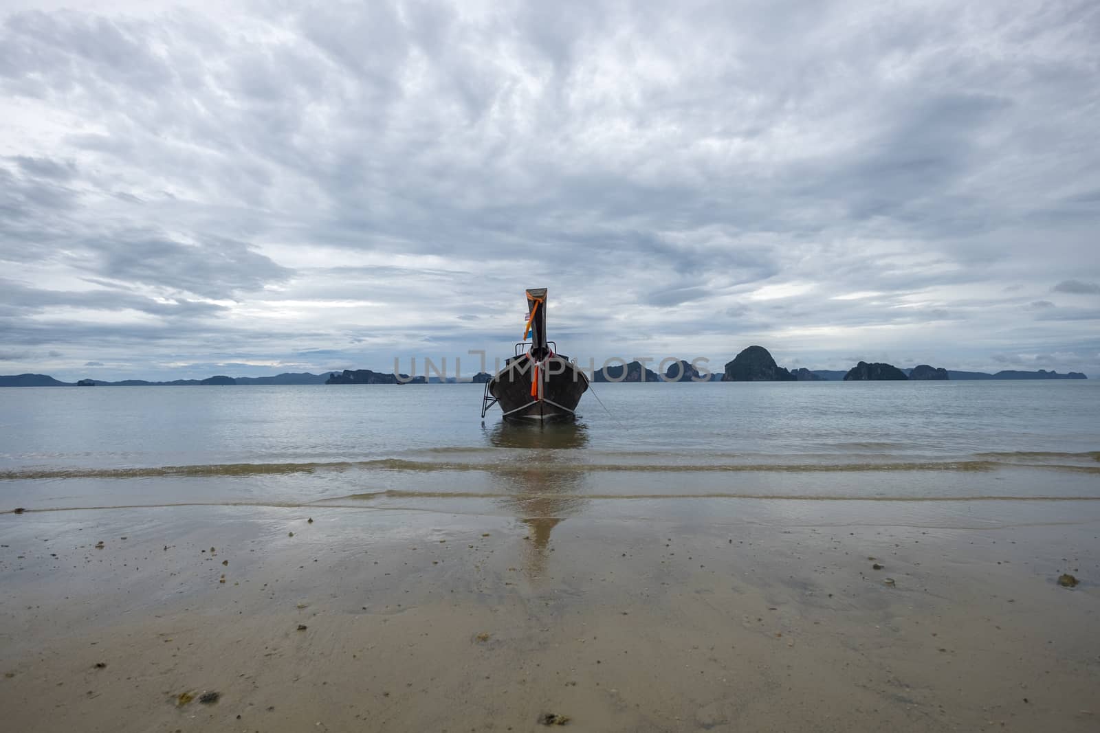 Traditional thai longtail boat near the beach in cloudy weather. Scenery rock islands in the background