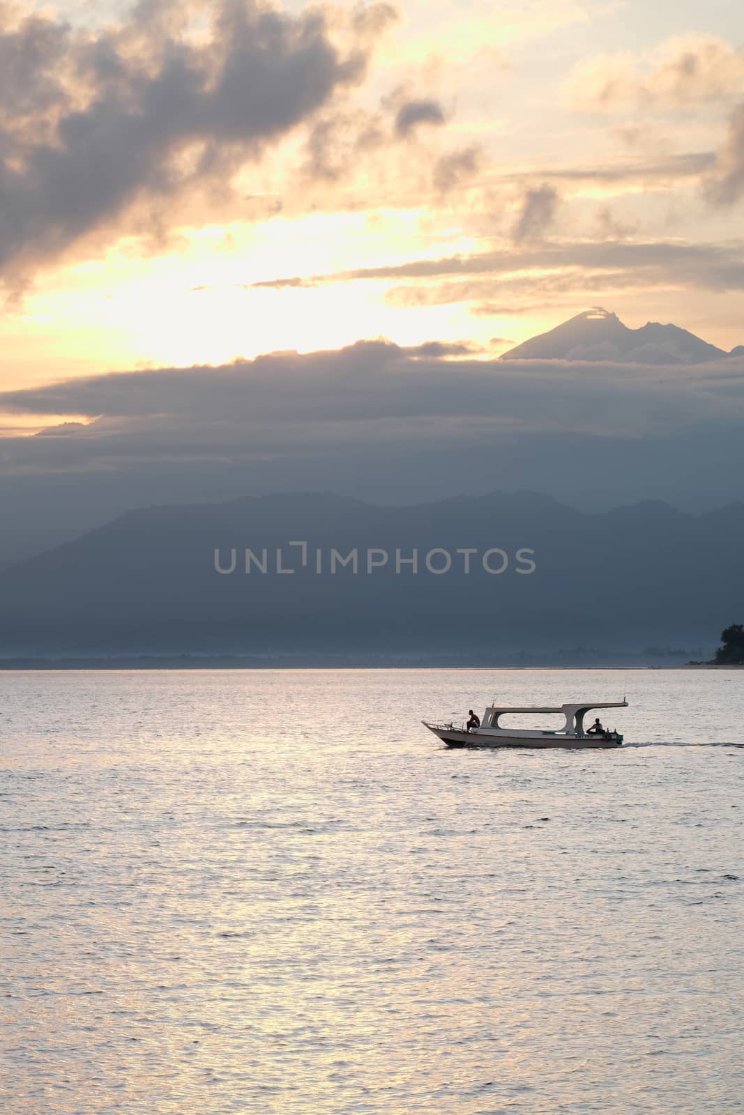 Indonesian fisherman in the boat early morning. Lombok volcano Rinjani in the background