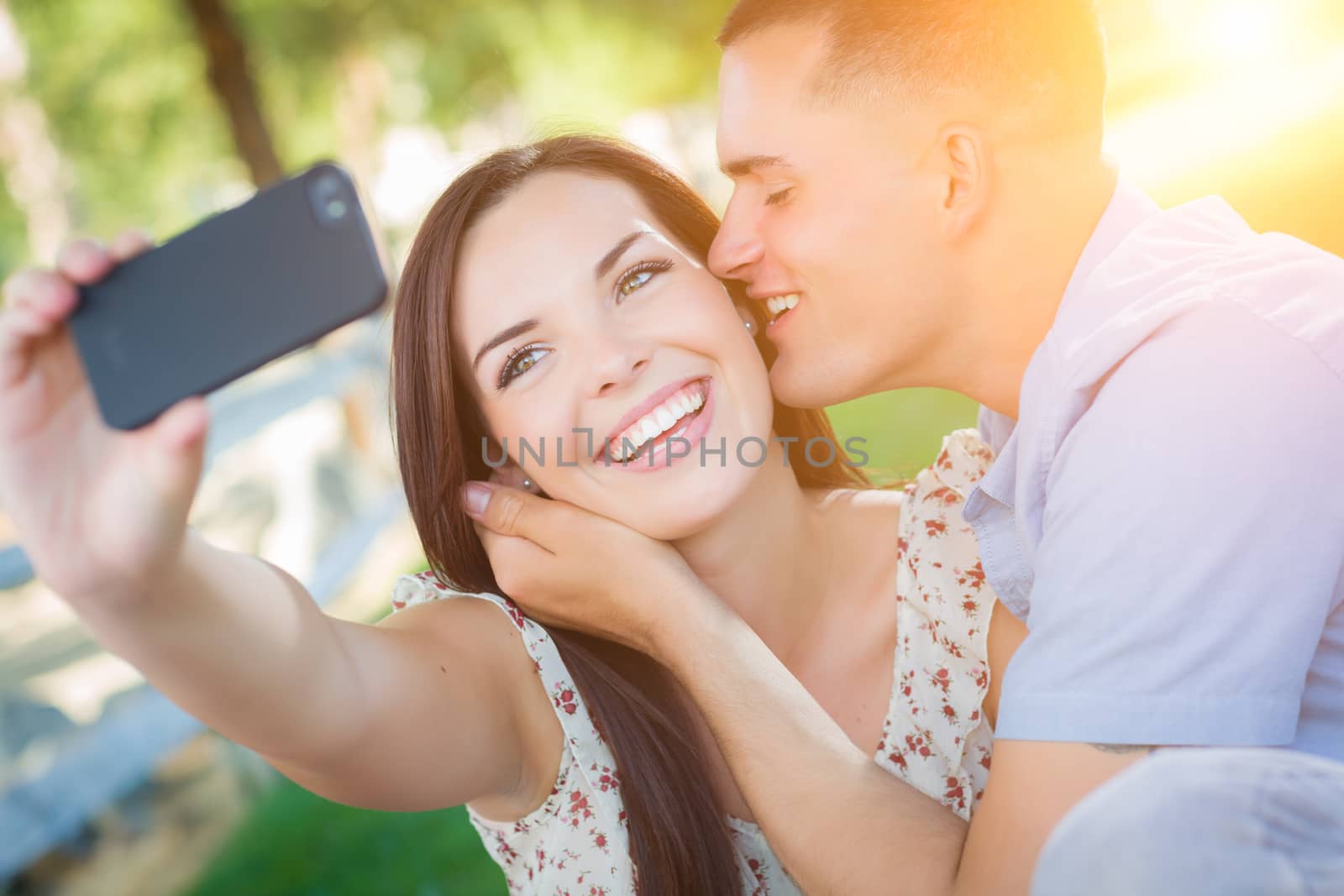 Happy Mixed Race Couple Taking Self Portrait with A Smart Phone in the Park.