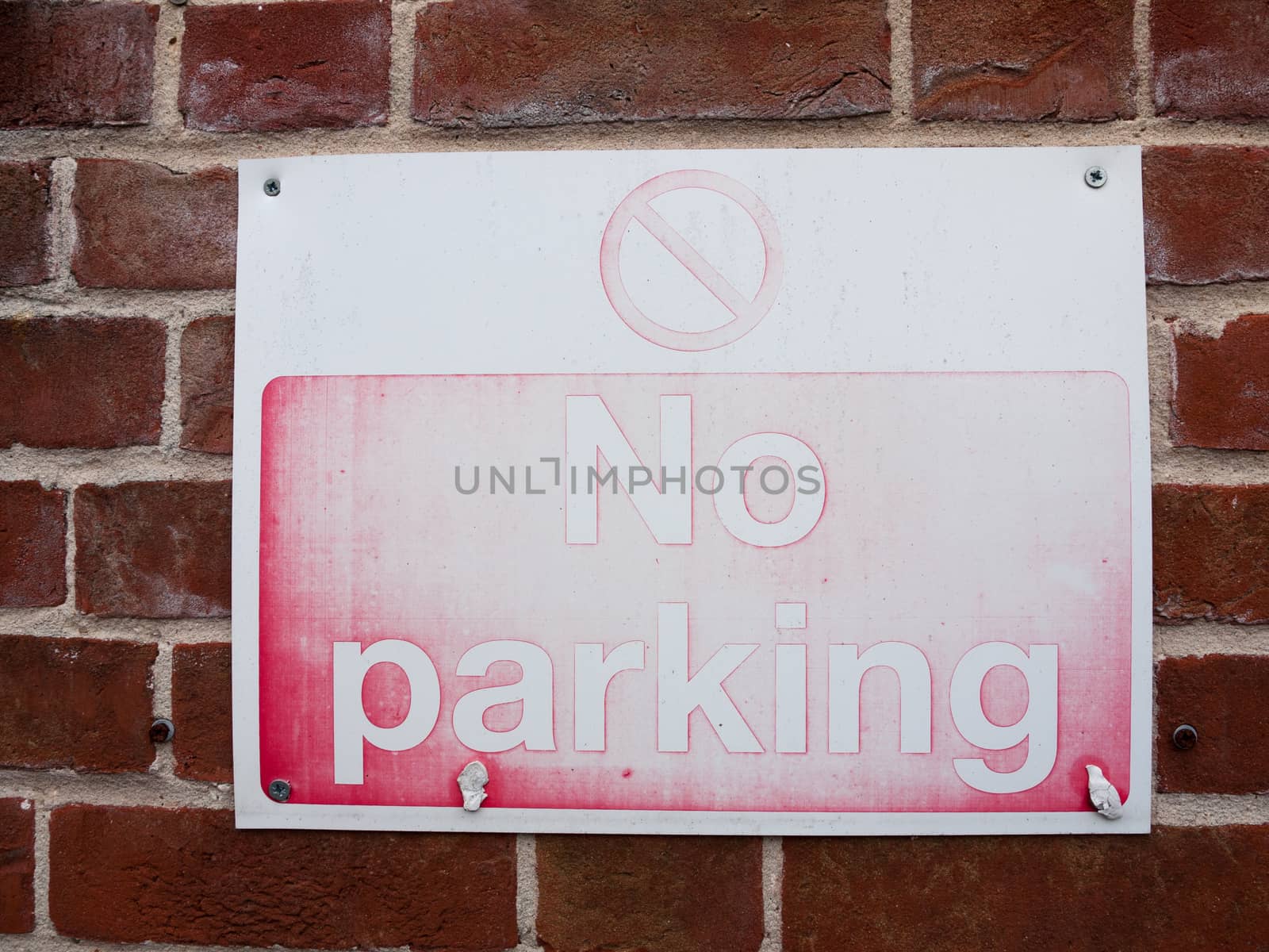 a faded red and white retro vintage no parking sign with texture and stained outside parking lot warning restrictions uk law driving rights no allowed private