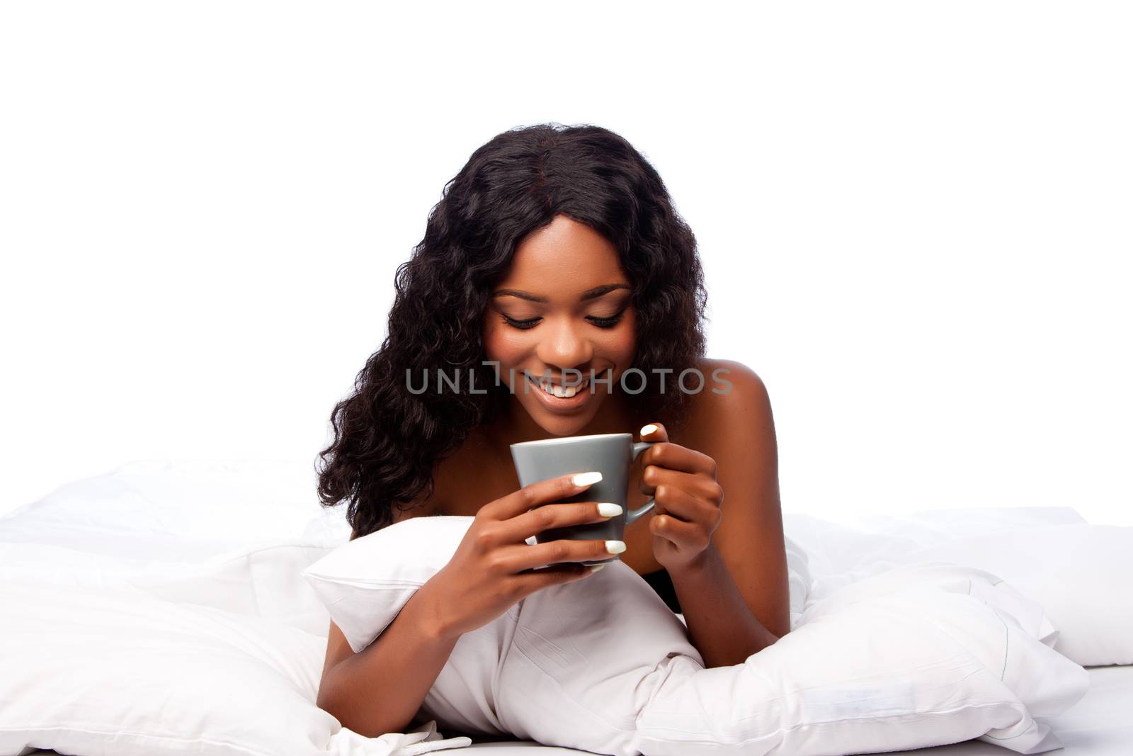 Beautiful happy smiling african woman with delicious coffee tea waking up in white bed.