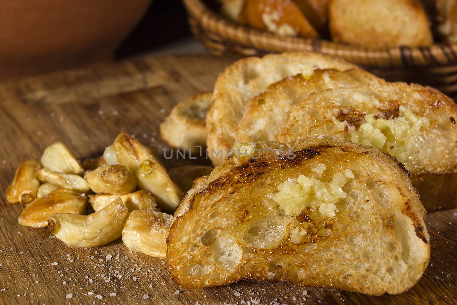 Fried garlic bread and garlic closeup on a wooden board