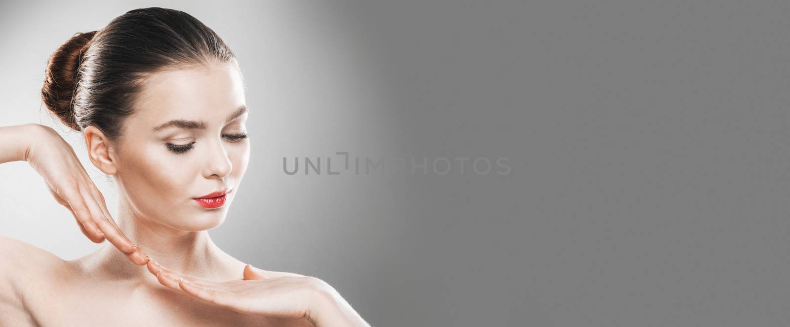 Beautiful young woman with clean fresh skin portrait on gray background with copy space