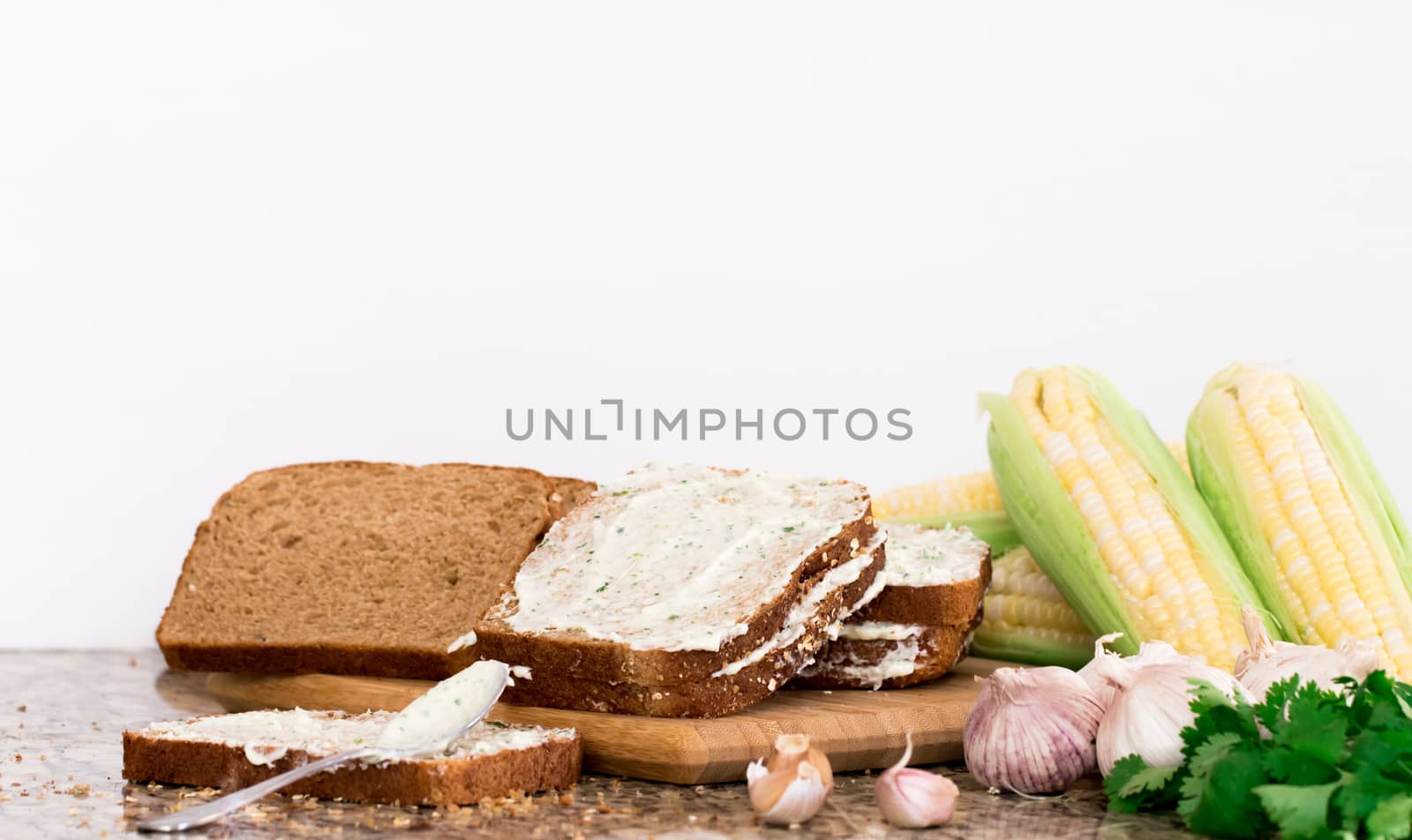 Prepare make garlic bread  on wooden block and herbs on marble table