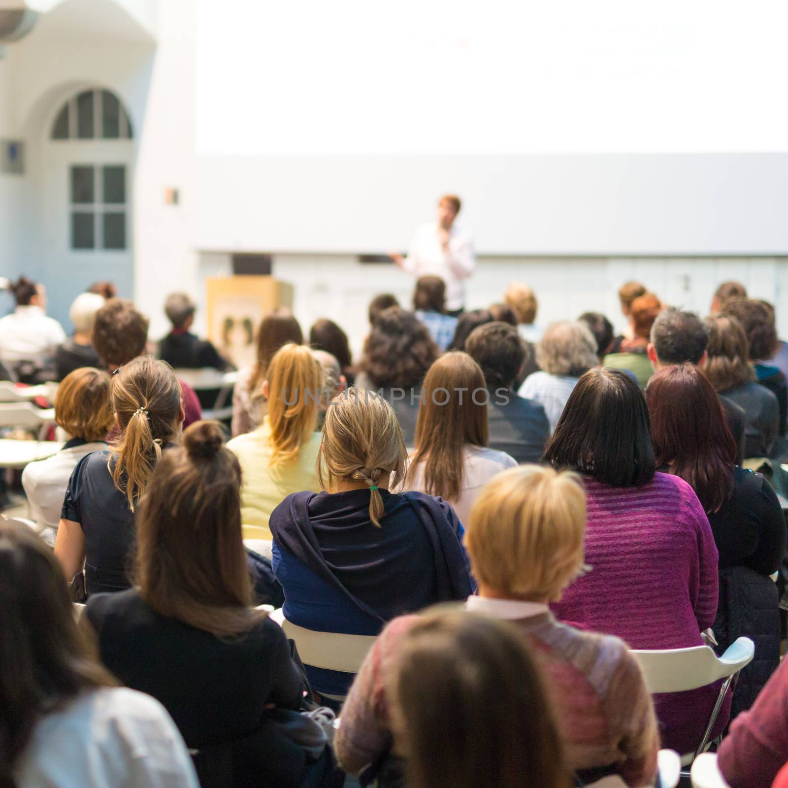 Woman giving presentation in lecture hall at university. by kasto