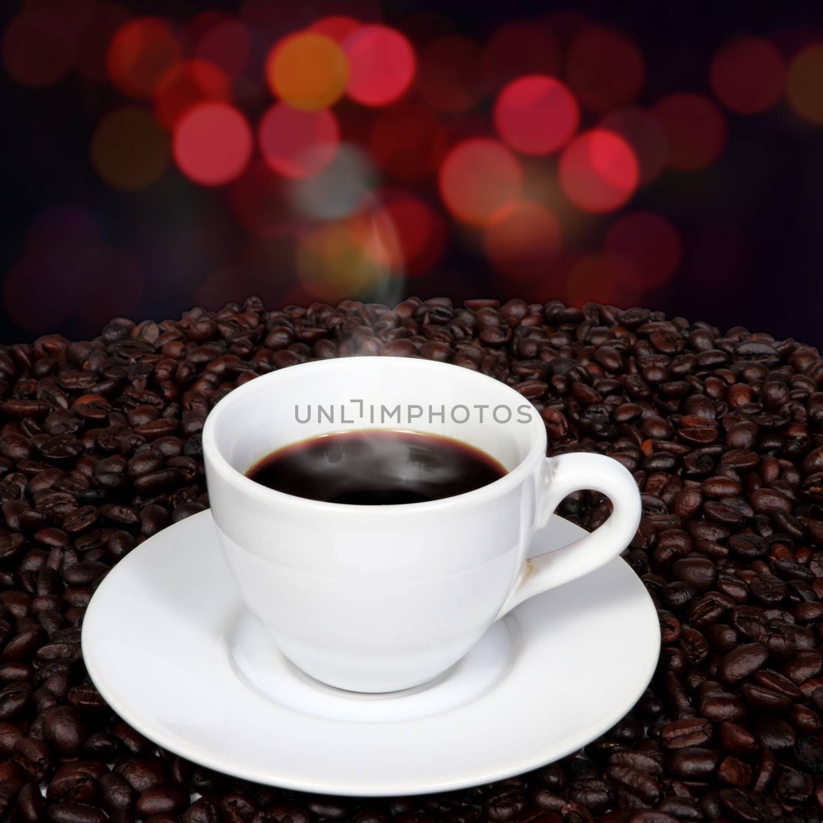 Black coffee and smoke in white cup over coffee beans with blurry night light background.