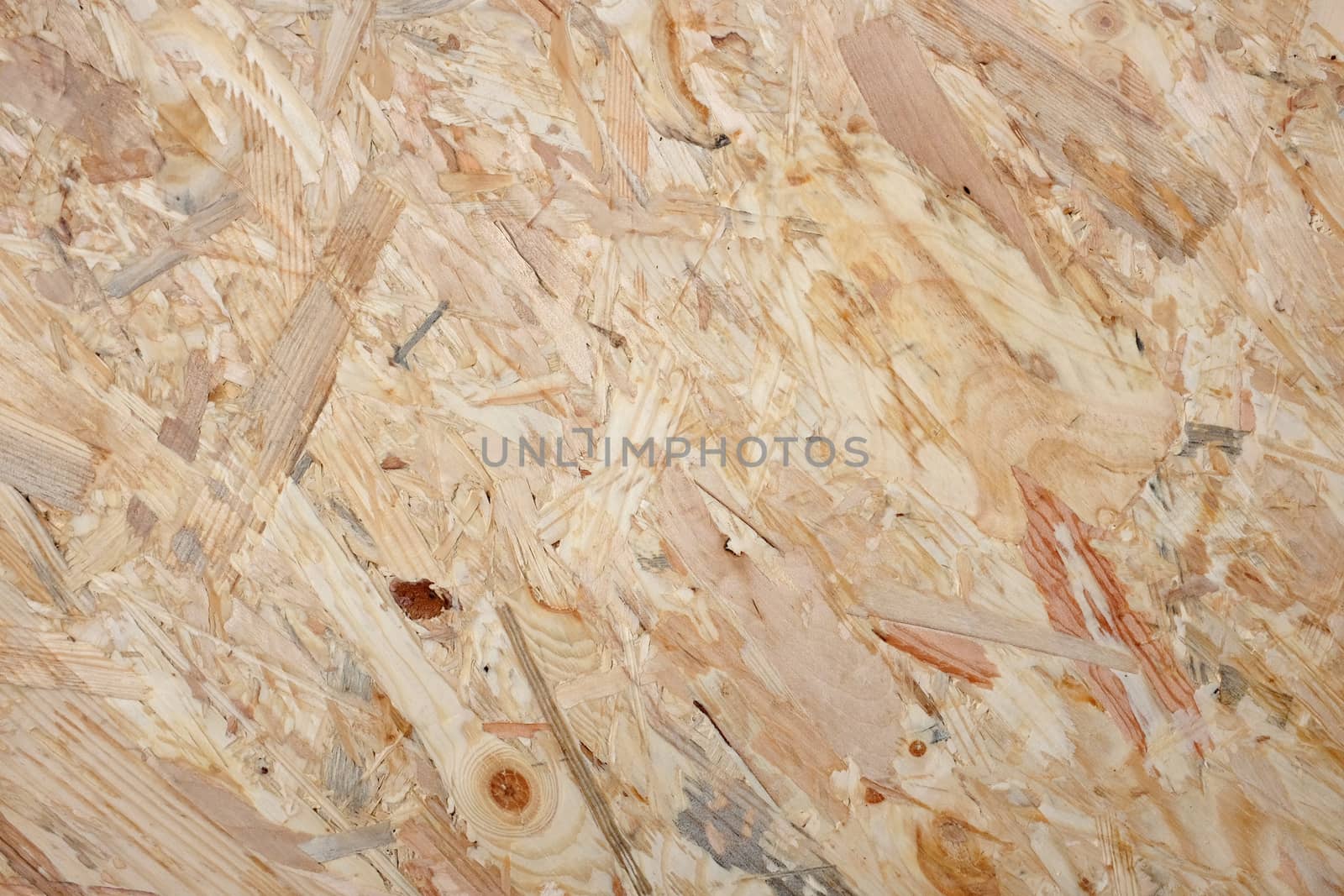 Coarse wooden flakeboard abstract background. Pale OSB sheet with dark wood knots and patterns.