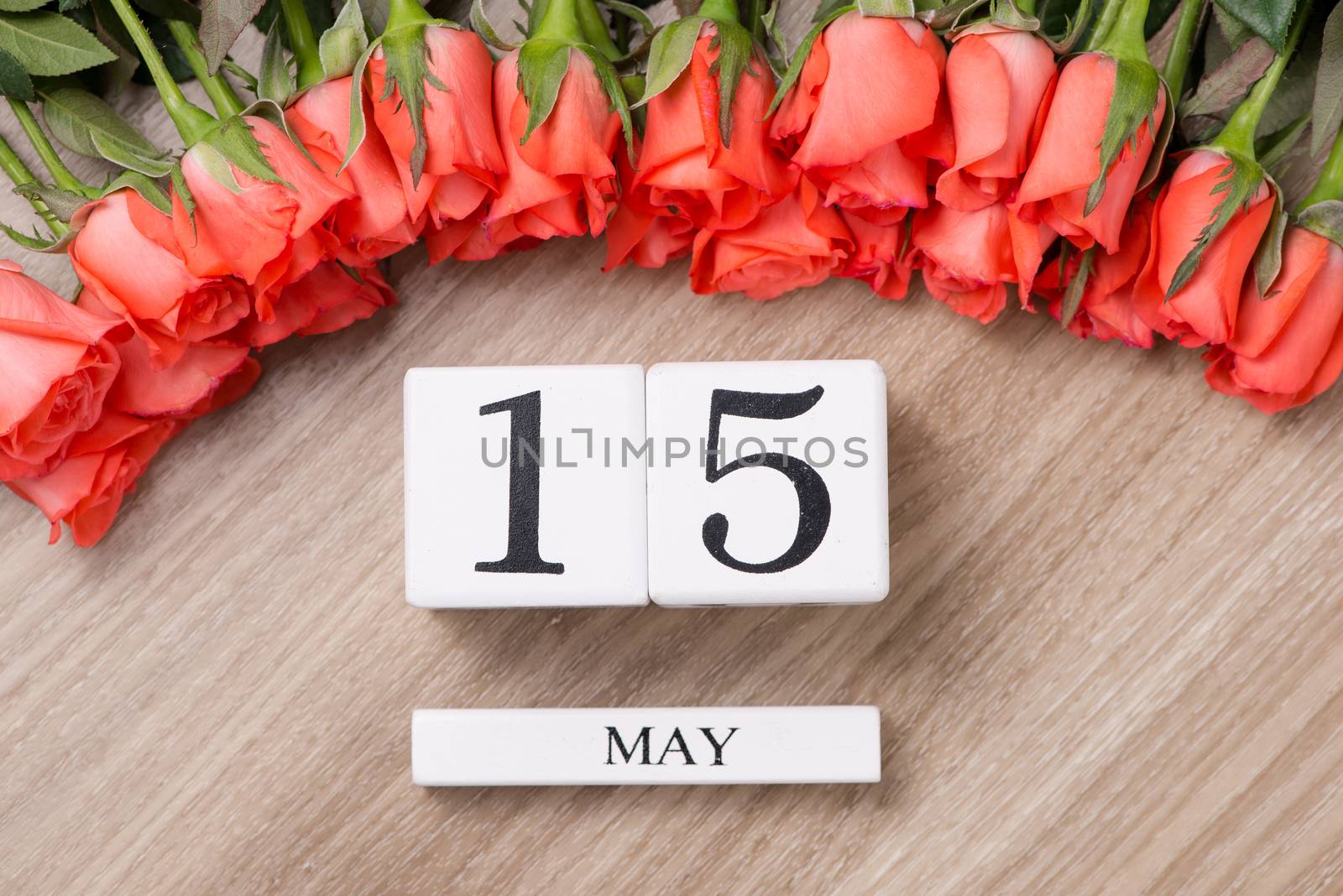 Cube shape calendar for MAY 15 on wooden table with roses