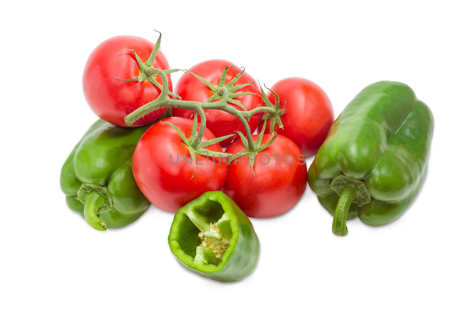 Branch with several ripe red tomatoes, two whole and one half of the green bell peppers closeup on a light background
