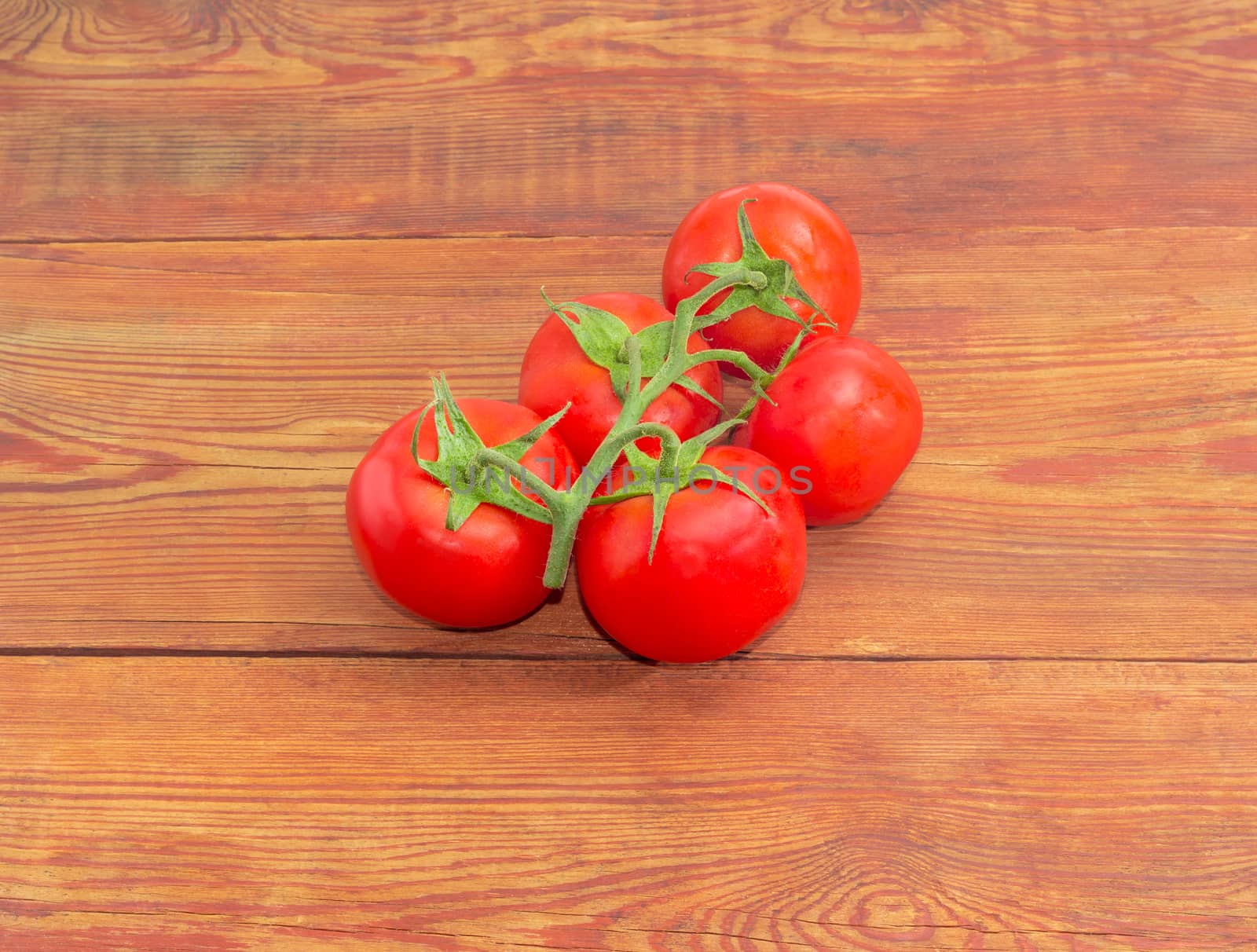 Branch of the ripe red tomatoes on the wooden surface by anmbph