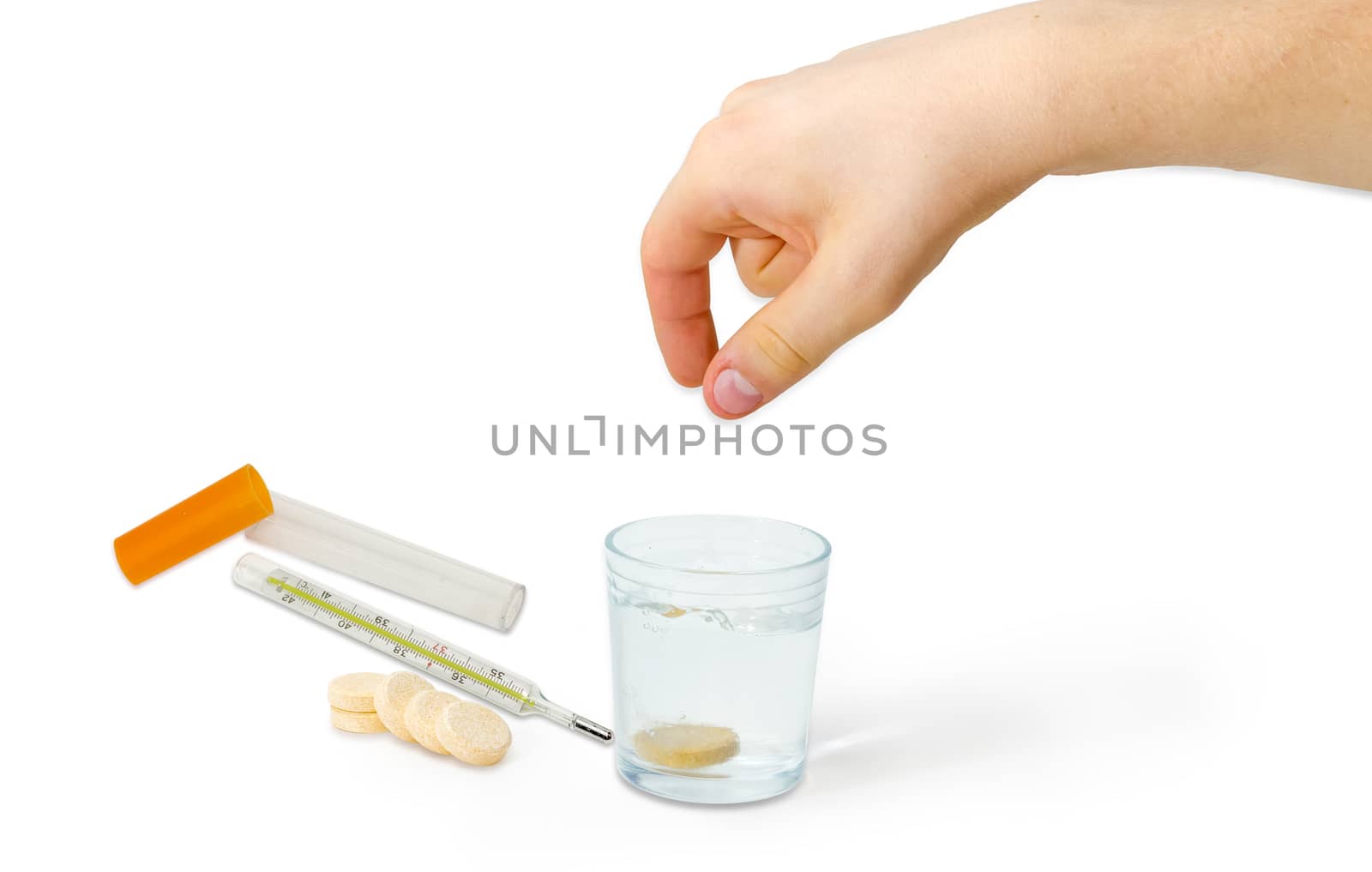 Effervescent medicinal tablet thrown into the glass of water by human hand, several same tablets beside and classic mercury medical thermometer on a light background
