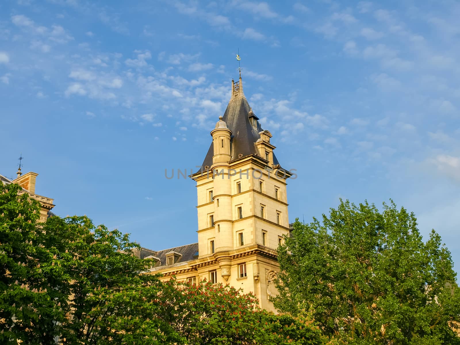 One of the towers of the southern facade of the Palace of Justice among flowering chestnuts in Paris

