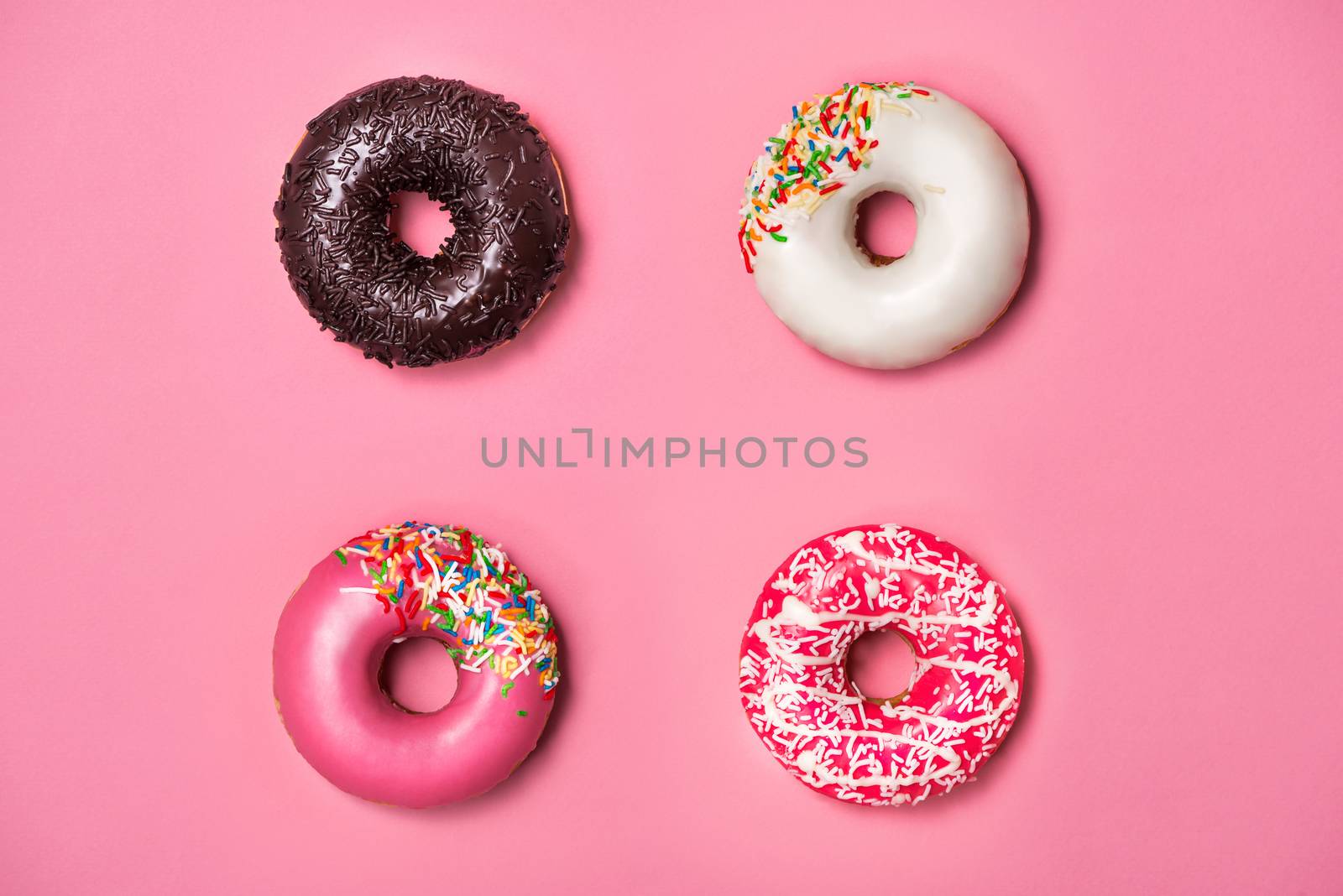Donuts with icing on pastel pink background. Sweet donuts. by makidotvn