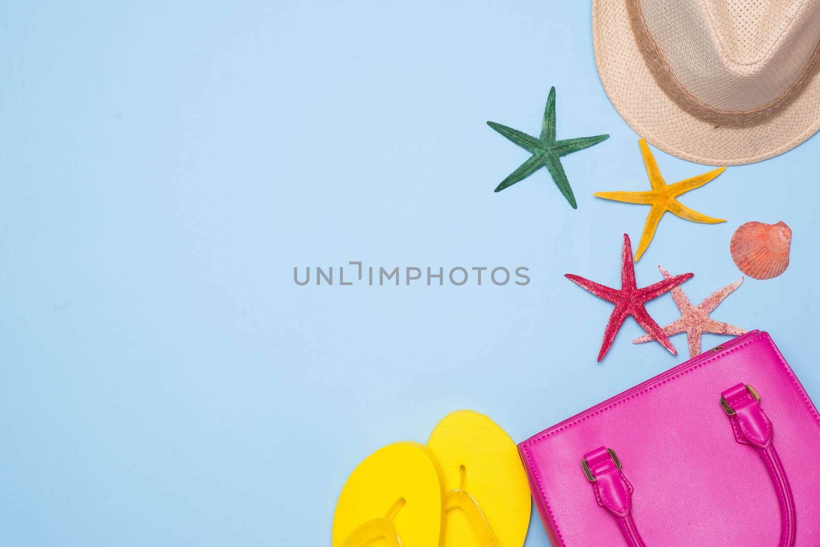 Summer concept. Pink handbag with accessories on light blue background