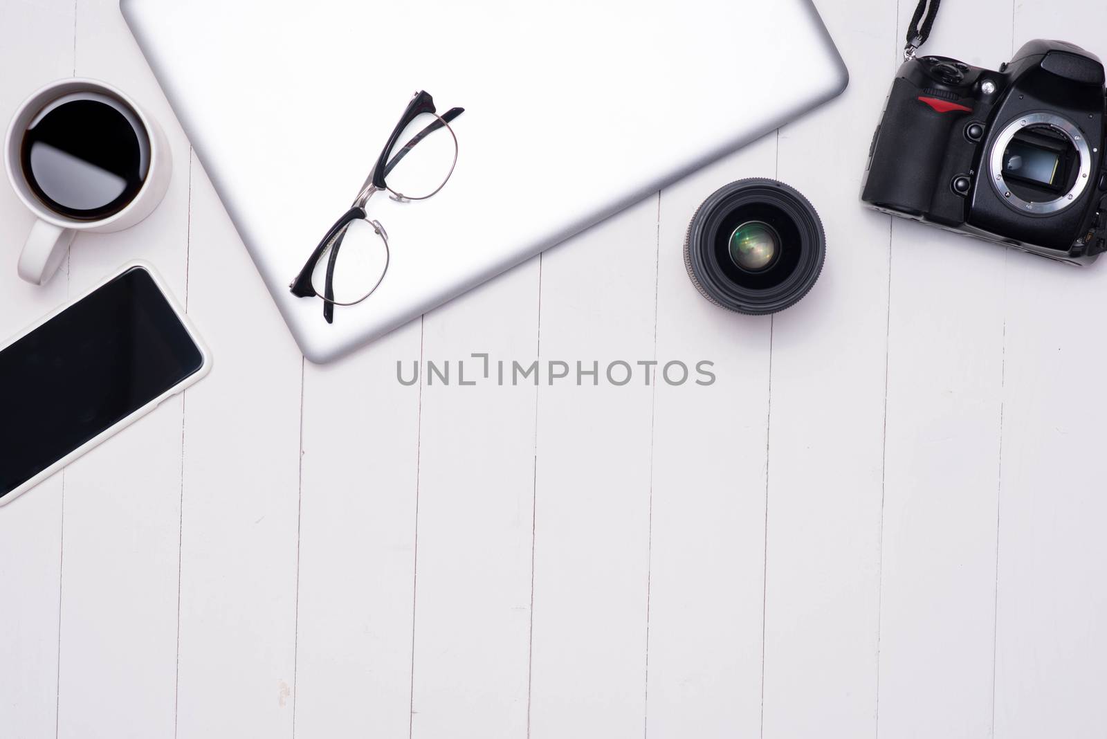 Flat lay photo of workspace desk with laptop, smartphone, coffee, eyeglasses and dslr camera