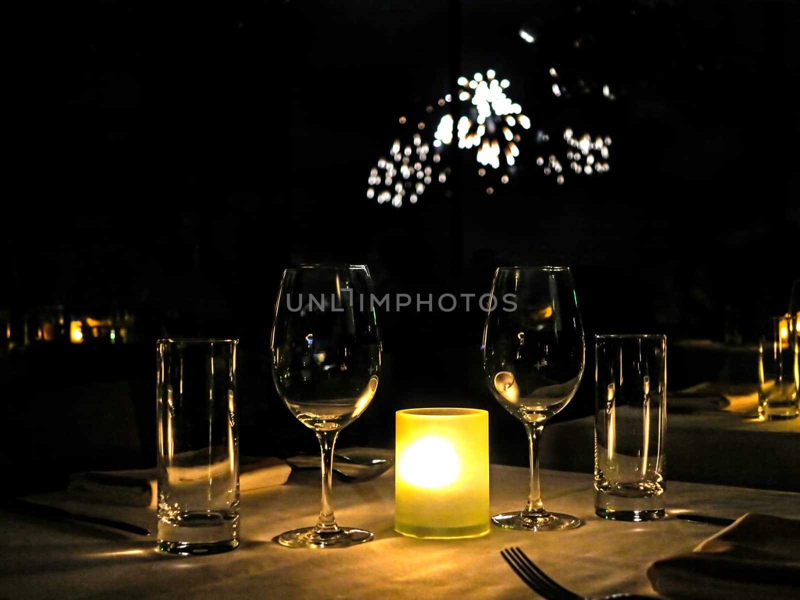 Some glasses on a table with fireworks behind