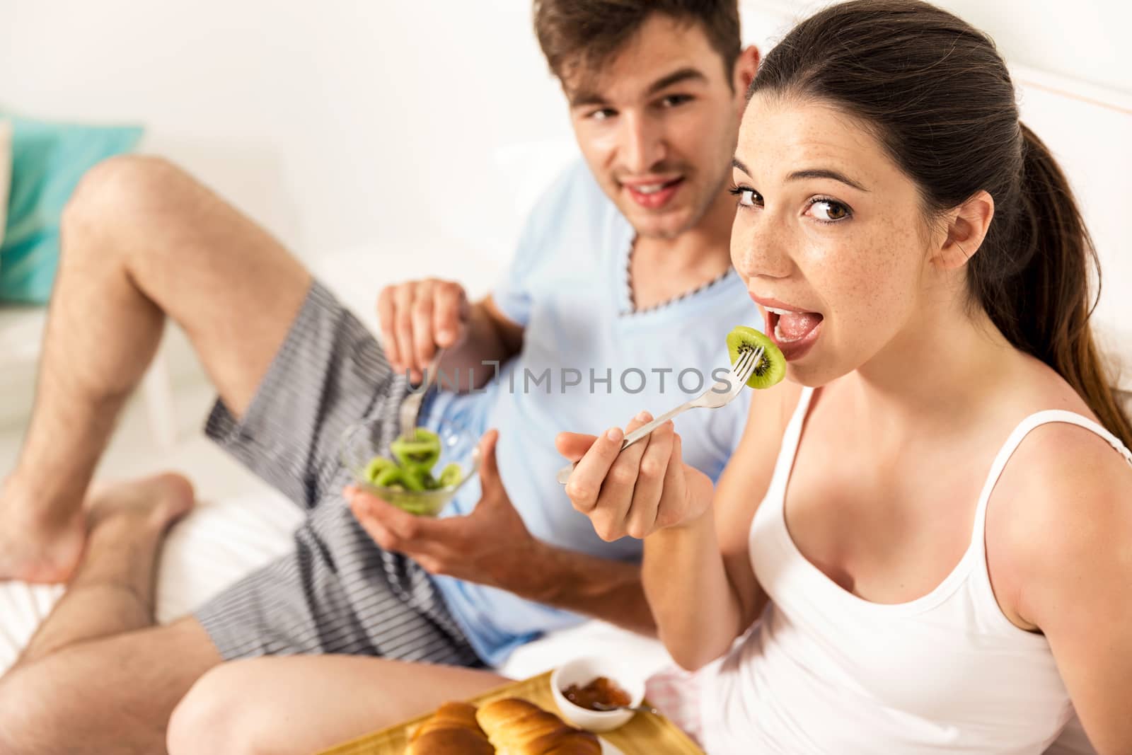 Young couple eating the breakfast on the bed