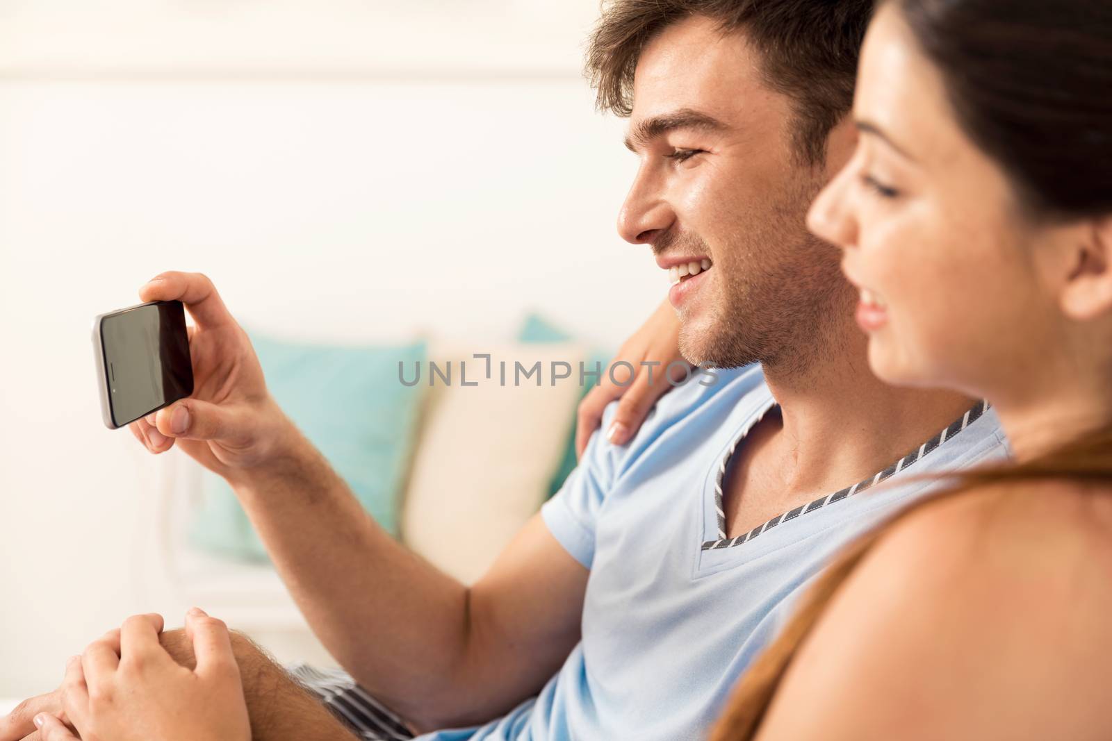 Young couple on bed watching videos on a cellphone